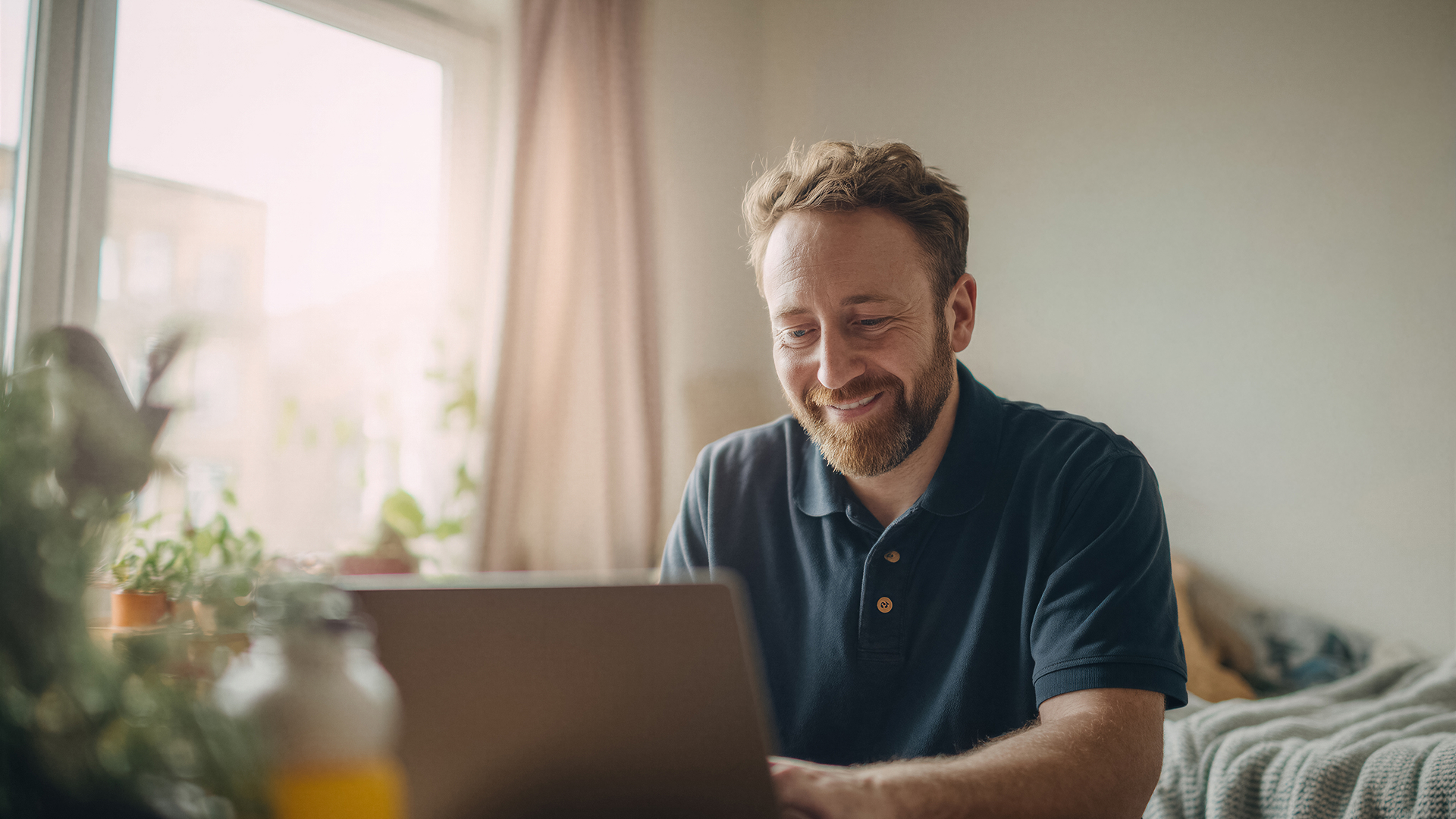 Un homme souriant travaille sur son ordinateur portable
